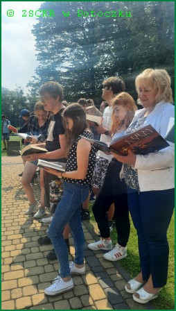 Akcja czytelnicza - Jak nie czytam, jak czytam, która odbyła się  08.06.2022 r. – ujęcie przed szkołą ZSCKR w Potoczku – nasi uczniowie i bibliotekarka czytający książkę.